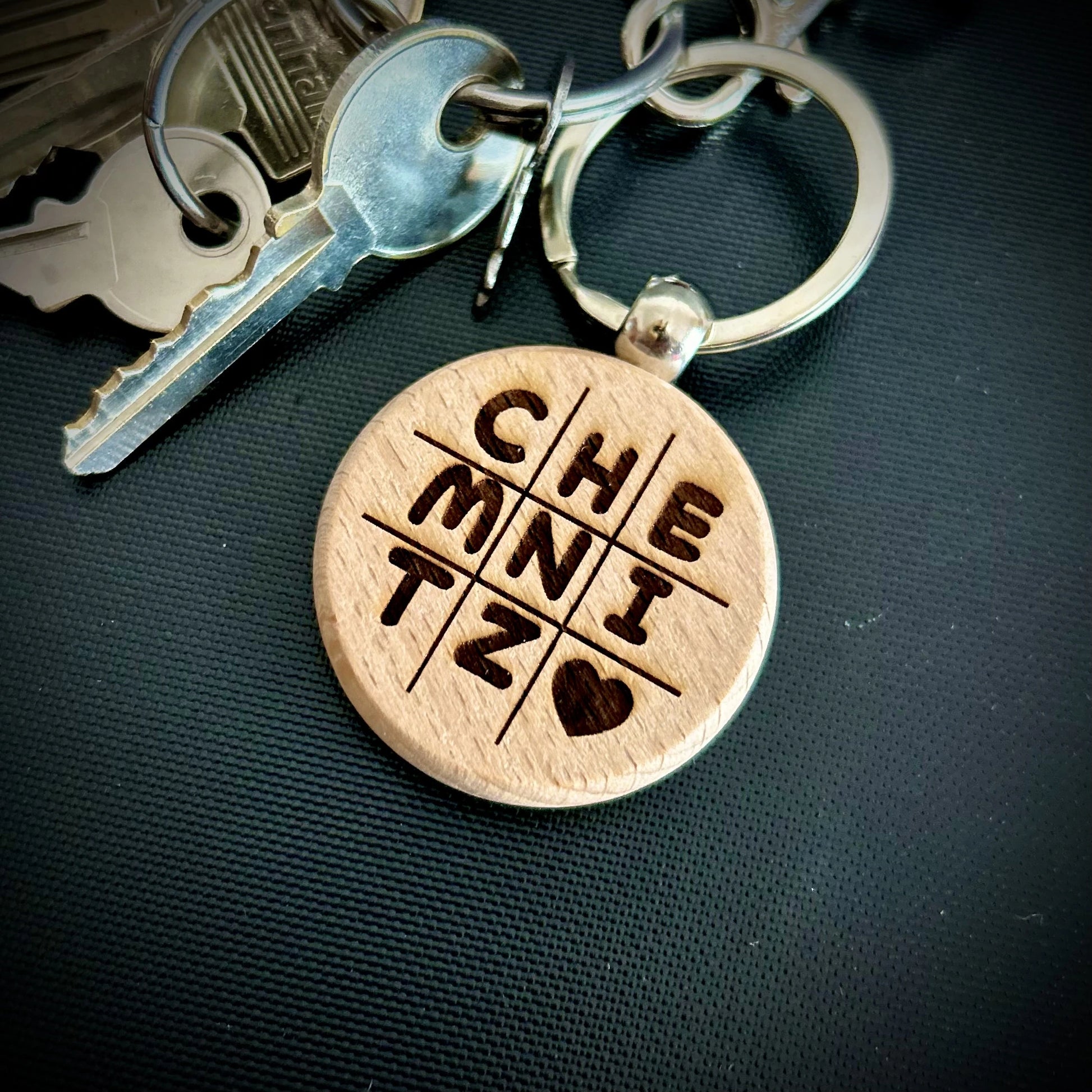 Runder Schlüsselanhänger aus Hol und eingebrannten Buchstaben "CHEMNITZ" als Merchandise oder Mitbringsel