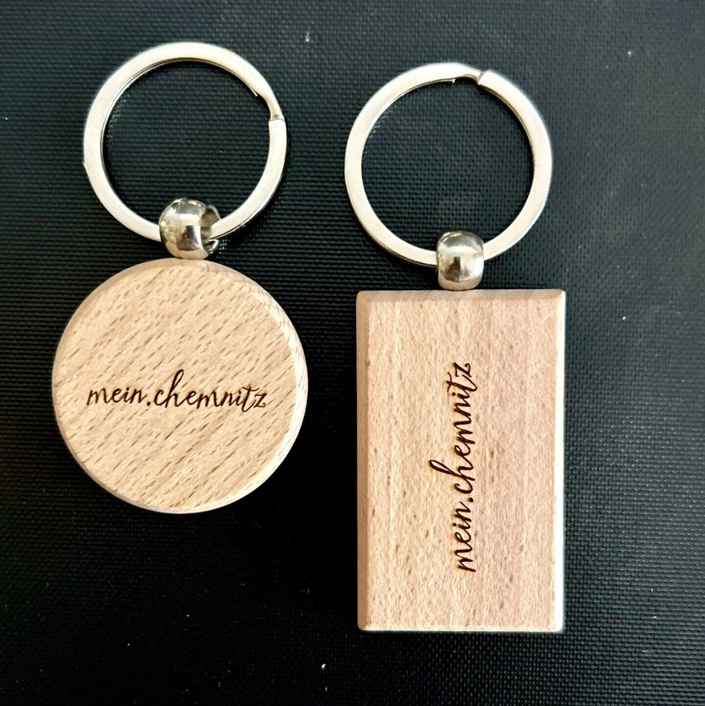 2 Schlüsselanhänger, rund und rechteckig, aus Holz mit dem Schriftzug "mein.chemnitz"